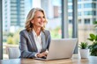 © Introvertia - Smiling businesswoman working on laptop in office
