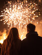 © Alona - A couple watching a fireworks display at night, the sky illuminated with bursts of red and white fireworks