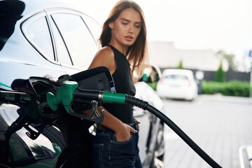 Wall Mural - A young woman at a gas station with her car