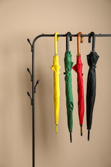 Wall Mural - Colorful umbrellas on rack near beige wall