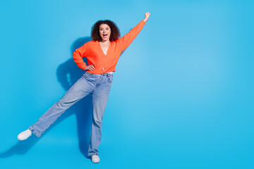 Wall Mural - Photo portrait of young strong latin superwoman with curly hairstyle raised fist up powerful isolated on blue color background