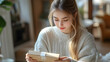© Siasart - A young woman opening a package with curiosity in a cozy setting.