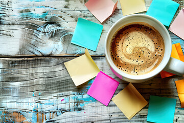 Coffee Cup Surrounded by Colorful Post-Its on Worn Blue Wooden Floor