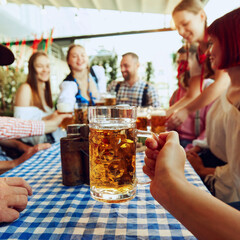 Wall Mural - Focus on lager beer mug and blurred people, friends sitting at table at bar and celebrating, drinking, talking. Concept of Oktoberfest, festival, party, brewery, traditions