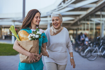 Nurse Assisting Elderly Woman While Carrying Groceries