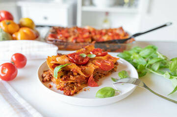 Wall Mural - Fresh and homemade pasta cassserole oder lasagna mit tomatoes and minced meat sauce on kitchen counter