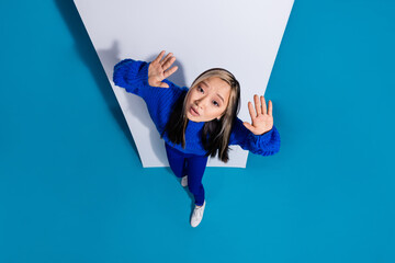 Wall Mural - Photo portrait of trendy korean girl raised hands up looking above like guilty smartphone touchscreen isolated on blue color background