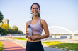 © Dragana Gordic - Young Woman Smiling While Exercising Outdoors with Water Bottle