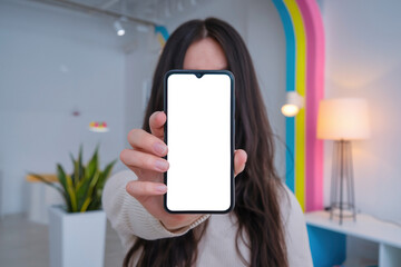 Woman showing smartphone with empty screen isolated on transparent background, colorful modern interior