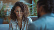© Mirjana - Young woman with curly hair engages in an earnest conversation indoors at a cozy, modern cafe during daylight