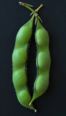 Two Seed Pods of Edamame, or Soybeans, Opened to Show Full, Ripe Beans Inside. Isolated on Black