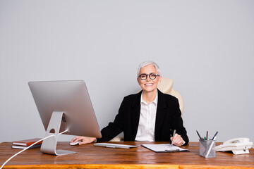 Wall Mural - Photo of attractive mature woman professional ceo sit table sign contract dressed formalwear specs isolated on gray color background