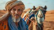 © Viktor - A man in a turban stands beside a camel in the desert's heart