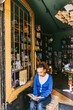 © Maskot - Young woman reading book while sitting near door at bookstore