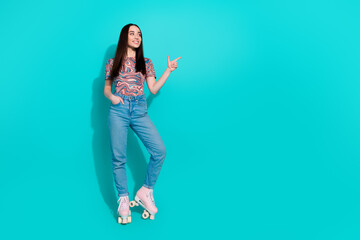 Wall Mural - Full length photo of adorable lovely girl wear striped t-shirt riding rollers pointing empty space isolated teal color background