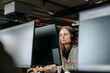 © Maskot - Focused female entrepreneur with wireless headphones doing coding on computer in office