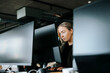 © Maskot - Focused female programmer doing coding on computer while sitting at desk in office