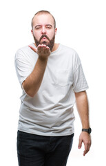 Canvas Print - Young caucasian hipster man wearing casual t-shirt over isolated background looking at the camera blowing a kiss with hand on air being lovely and sexy. Love expression.