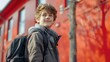 © Synthetica - A young boy wearing a backpack and a scarf stands in front of a red building