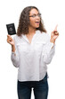 © Krakenimages.com - Young hispanic woman holding passport of United States of America very happy pointing with hand and finger to the side