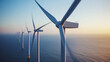 ©  Himadness - A row of offshore wind turbines against the backdrop of the ocean at sunset, symbolizing renewable energy and sustainable power generation.