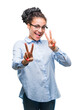 © Krakenimages.com - Young braided hair african american business girl wearing glasses over isolated background smiling looking to the camera showing fingers doing victory sign. Number two.