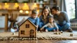 © Arieswanto - Wooden House Model with Blurred Family in the Background