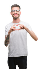 Sticker - Young tattooed adult man smiling in love showing heart symbol and shape with hands. Romantic concept.