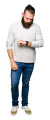 Young blond man wearing casual sweater Checking the time on wrist watch, relaxed and confident