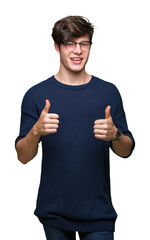 Young handsome man wearing glasses over isolated background success sign doing positive gesture with hand, thumbs up smiling and happy. Looking at the camera with cheerful expression, winner gesture.