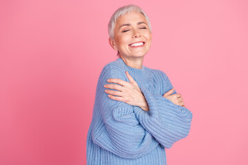 Poster - Photo portrait of pretty retired female hugging self enjoy warmth wear trendy blue knitwear outfit isolated on pink color background