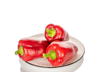 Three sweet red peppers on a ceramic plate, macro, isolated on white background.