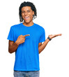 © Krakenimages.com - Young african american man wearing casual clothes amazed and smiling to the camera while presenting with hand and pointing with finger.