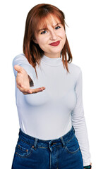 Canvas Print - Redhead young woman wearing casual turtleneck sweater smiling cheerful offering palm hand giving assistance and acceptance.