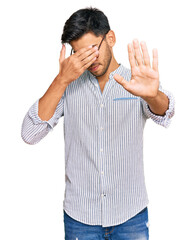 Wall Mural - Young handsome man wearing casual clothes and glasses covering eyes with hands and doing stop gesture with sad and fear expression. embarrassed and negative concept.