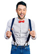 © Krakenimages.com - Hispanic man with beard wearing hipster look holding suspenders smiling and laughing hard out loud because funny crazy joke.