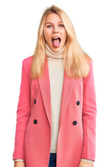 Young beautiful blonde woman wearing elegant clothes sticking tongue out happy with funny expression. emotion concept.