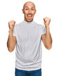 © Krakenimages.com - Bald man with beard wearing casual white t shirt celebrating surprised and amazed for success with arms raised and open eyes. winner concept.