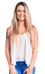 Wall Mural - Young beautiful blonde woman wearing sleeveless t-shirt looking positive and happy standing and smiling with a confident smile showing teeth