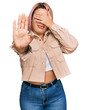 © Krakenimages.com - Hispanic woman with pink hair wearing casual clothes covering eyes with hands and doing stop gesture with sad and fear expression. embarrassed and negative concept.