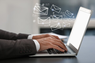 Man using laptop at table, closeup. E-mail address signs and envelopes over computer