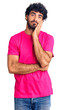 © Krakenimages.com - Handsome young man with curly hair and bear wearing casual pink tshirt thinking looking tired and bored with depression problems with crossed arms.