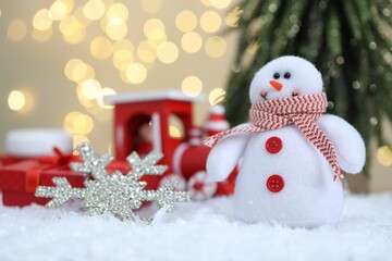 Wall Mural - Funny snowman figure and other Christmas decor on artificial snow against blurred lights