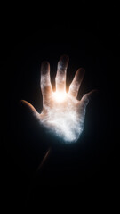 Illuminated hand reaching out, glowing with energy against a dark background, symbolizing power, creation, and mysticism