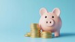 © Tendo - cute pink piggy bank with a stack of gold coins on a light blue background. Concept of saving money for the future or family budget.