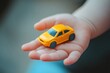 © Tombomumet Studio - Toddler's hand holding a toy car. Children's toys