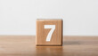 © hardvicore - Wooden cube with number 7 on wooden table, white wall on background. Event planner, calendar