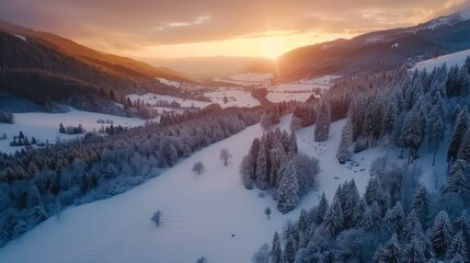 Wall Mural - Aerial view of a snow-covered valley with a golden sunrise behind the mountains.