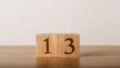 © hardvicore - Wooden cube with number 13 on wooden table, white wall on background. Event planner, calendar