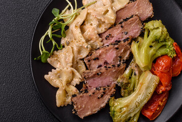 Bowl with slices of baked tuna with broccoli, tomatoes and fusili pasta